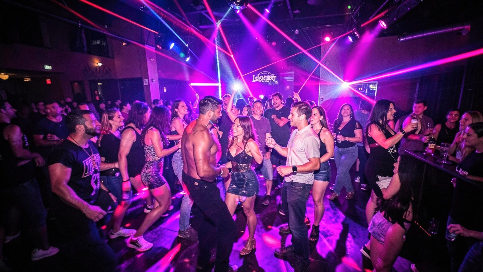 Friends dancing together under pink and violet lasers at a Los Angeles nightclub